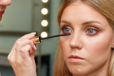 Makyöz, modelin şehvetli kirpiklerini oluşturuyor. Makyaj yapma süreci.