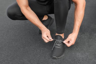 Genç erkek koşucu sporcu antrenmanı yapıyor ve şehir dışında spor yapıyor. Koşu ayakkabısı bağlayan adam.