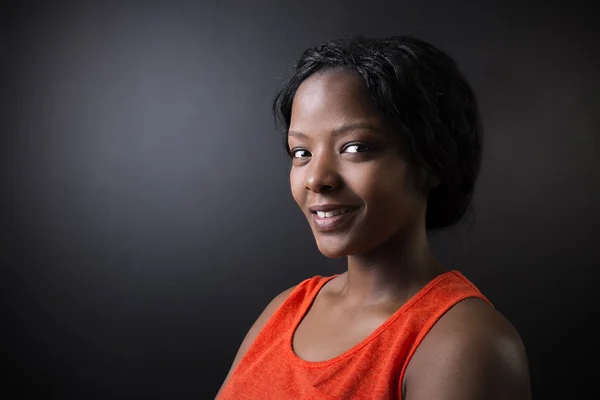 South African or African American woman teacher on chalk black board background — Stock Photo, Image