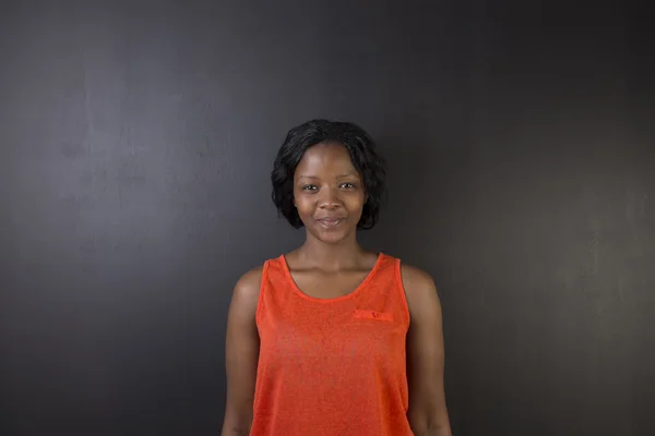 South African or African American woman teacher or student against a dark blackboard background — Stock Photo, Image