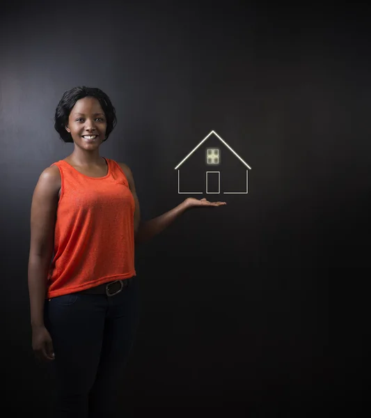 Maestra o estudiante sudafricana o afroamericana contra fondo negro con casa o bienes raíces — Foto de Stock