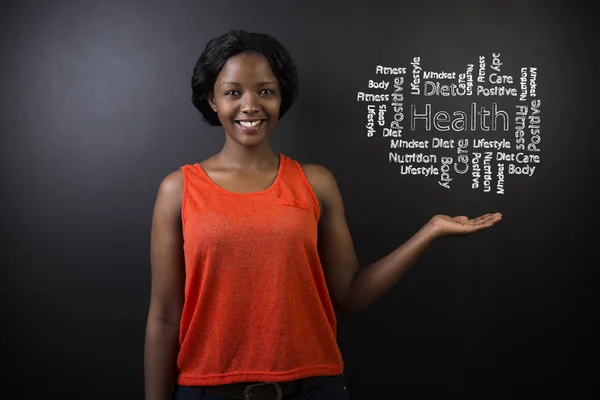 South African or African American woman teacher or student against blackboard health diagram — Stock Photo, Image