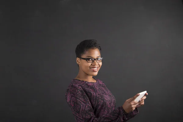 African woman with tablet on blackboard background — Stok fotoğraf