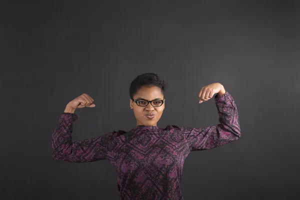 African woman with strong arms on blackboard background — Stok fotoğraf