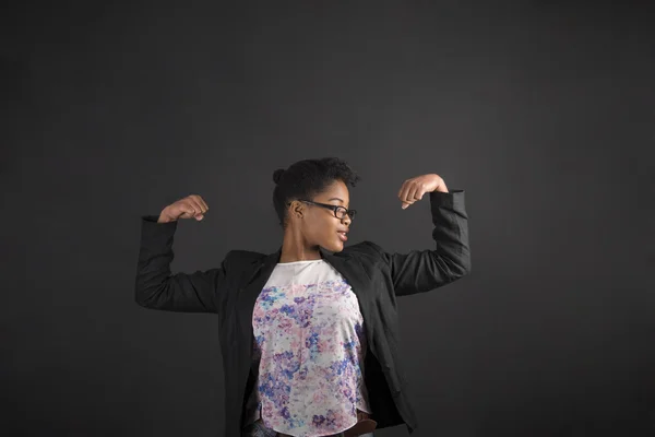 African woman with strong arms on blackboard background — 스톡 사진