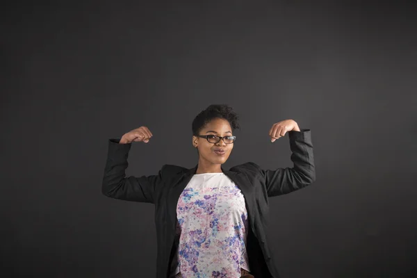 Femme africaine avec des bras forts sur fond de tableau noir — Photo