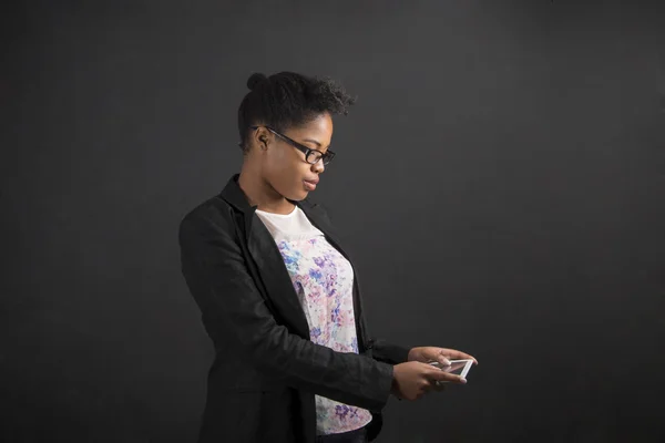 African woman with tablet on blackboard background — Zdjęcie stockowe