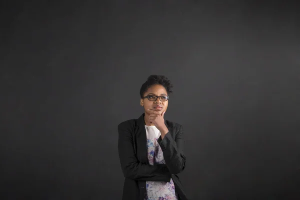 African woman with hand on chin thinking on blackboard background — Stok fotoğraf