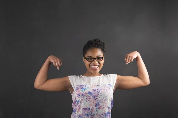 African woman with strong arms on blackboard background — ストック写真