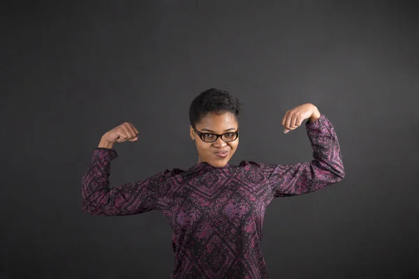 African woman with strong arms on blackboard background Stockfoto