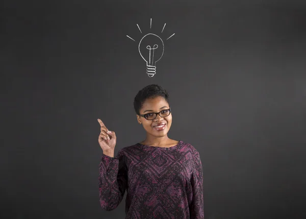 African American woman good idea with lightbulb on blackboard background — Zdjęcie stockowe