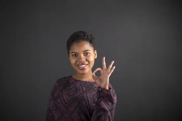 African American woman with perfect hand signal on blackboard background — Stock Photo, Image
