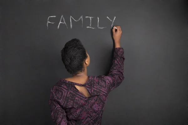 African American woman teacher writing family on chalk black board background — ストック写真