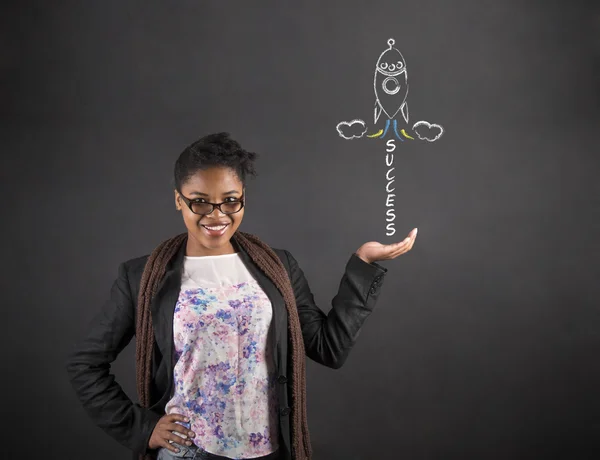 Africano mulher segurando mão para fora com sucesso foguete no fundo blackboard — Fotografia de Stock