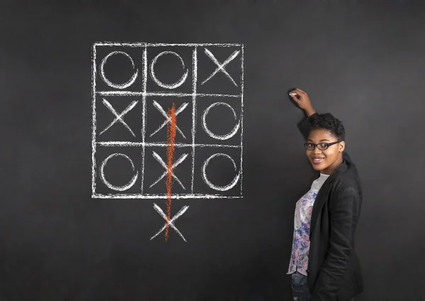 Південноафриканський або афро-американських жінка вчитель написання tic tac toe крейда чорна рада фону — стокове фото