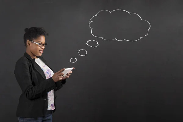 Afrikaanse vrouw met Tablet PC-spraak of gedachte zeepbel op blackboard achtergrond — Stockfoto