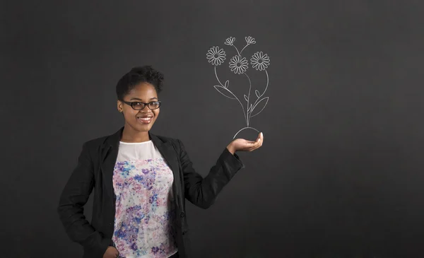 Africano mulher segurando mão para fora com crescente flor no fundo blackboard — Fotografia de Stock