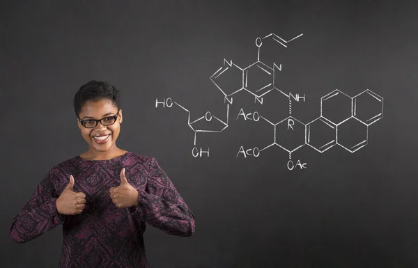 African woman with thumbs up hand signal with science on blackboard background — Stock Photo, Image