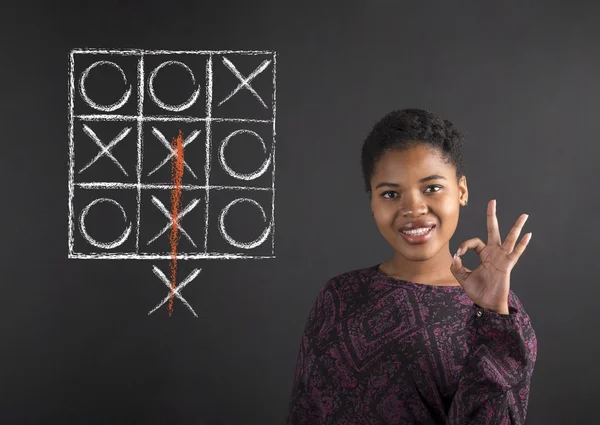 Donna afro-americana con perfetto segnale a mano con un diagramma tic tac toe su sfondo lavagna — Foto Stock