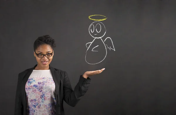 African woman holding hand out showing an angel on blackboard background — 图库照片
