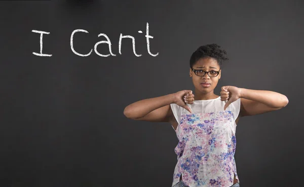 African woman with thumbs down hand signal I Can't on blackboard background — стокове фото