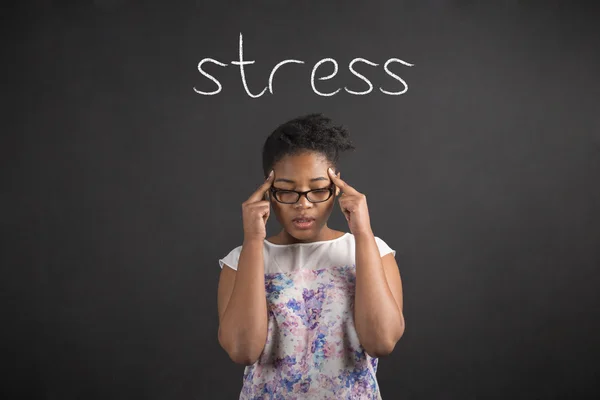 African woman with fingers on temples thinking about stress on blackboard background — Stok fotoğraf