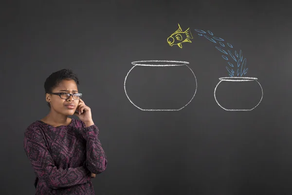 African woman with hand on chin thinking jumping fish on blackboard background — ストック写真