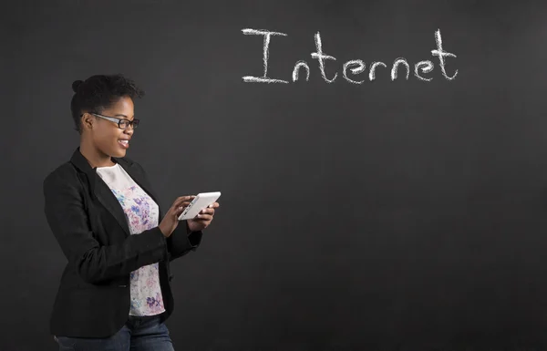 African woman with tablet with Internet word on blackboard background — ストック写真