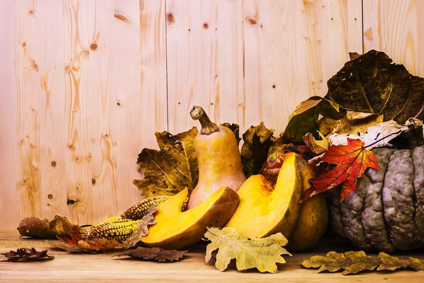 Zucche e foglie su sfondo di legno — Foto Stock