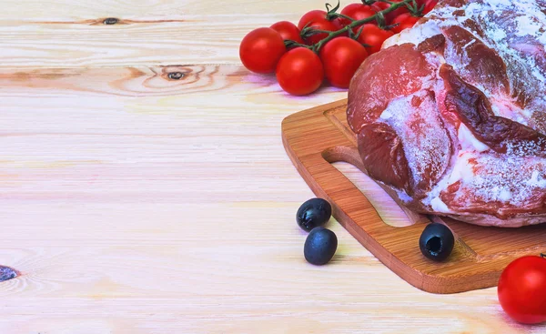Raw meat on ice and tomatoes. — Stock Photo, Image
