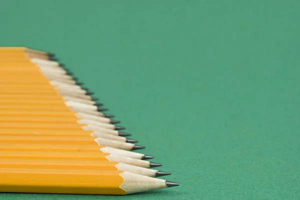Linie von Bleistiften auf grünem Hintergrund — Stockfoto