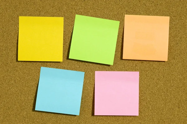 Notas pegajosas em cores diferentes na placa de cortiça com espaço de cópia — Fotografia de Stock