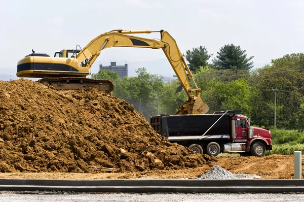 Escavadeira que carrega o caminhão basculante no local de construção — Fotografia de Stock
