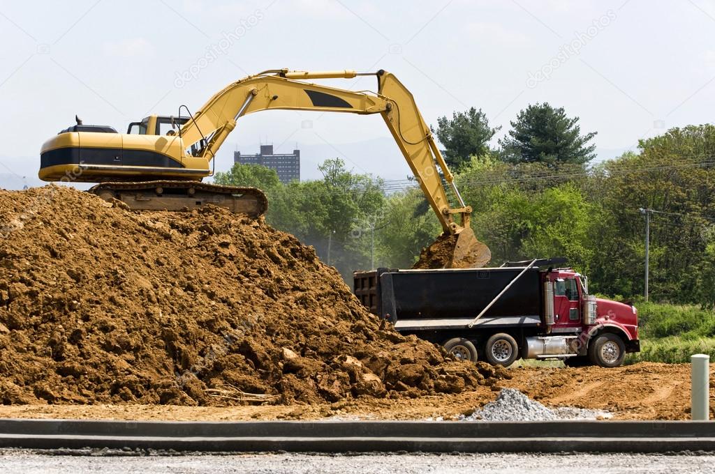 Excavator Loading Dump Truck At Construction Site