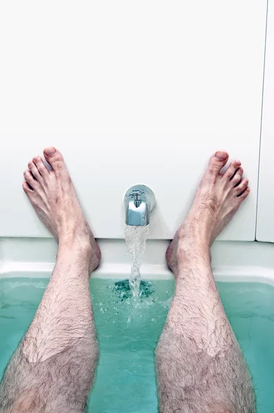 Wasser läuft in einer Wanne, während Mann entspannt — Stockfoto