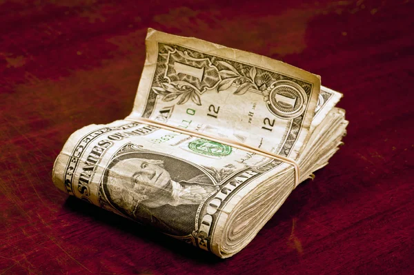 Gran fajo de billetes de dólar con banda de goma en un mostrador — Foto de Stock
