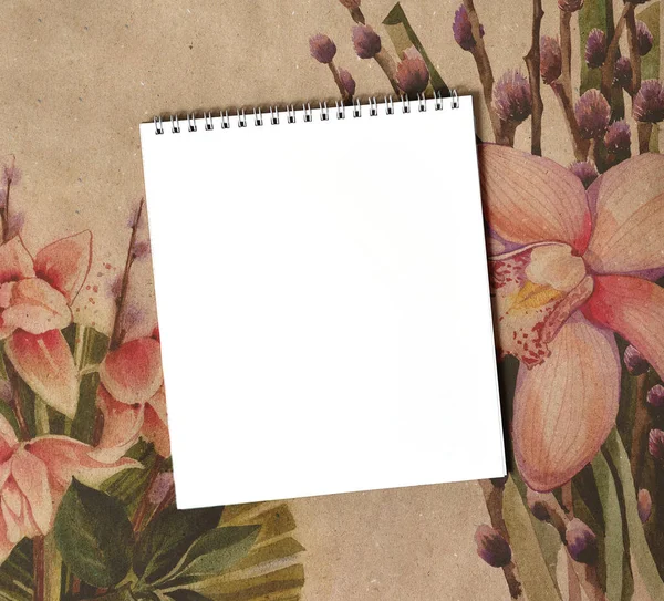 Blank notepad close up on craft paper with flowers.