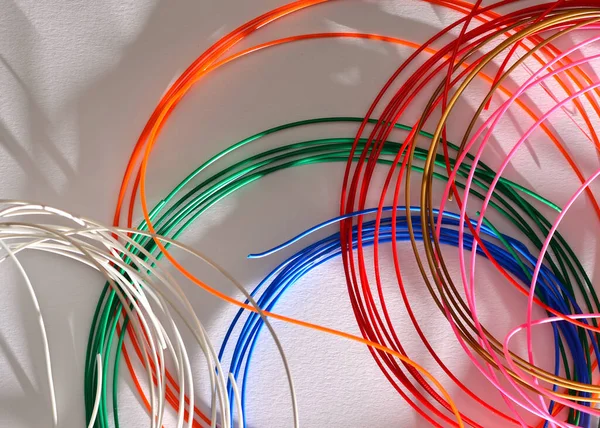 Matasse colorate di filo di plastica per una penna 3D si trovano caoticamente uno sopra l'altro su uno sfondo bianco. — Foto Stock