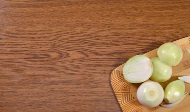 Ahşap desenli bir masada soyulan soğanlar..