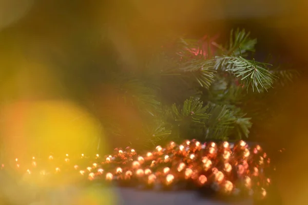 Weihnachten Hintergrund mit verschwommenen Lichtern, grünen Zweigen eines Weihnachtsbaums, orangefarbenen runden Perlen. Neujahr und Weihnachten. — Stockfoto