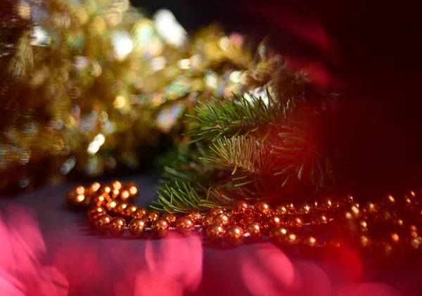 Orange beads with round beads to decorate the Christmas tree, close-up against a background of blurred red light from the lamps. — Stock Photo, Image