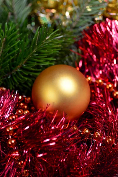 Abstract Nieuwjaar en kerstachtergrond. Rood en goud tinsel, binnen ligt een gouden bal kerstboom speelgoed, de achtergrond is wazig. — Stockfoto