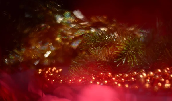 Christmas background with blurred red lights, green branches of a Christmas tree, orange round beads. New Years and Christmas. — Stock Photo, Image