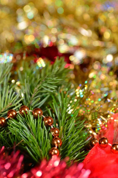 Festive background with gold and red tinsel, orange beads, green spruce branches. Vertical. — Stock Photo, Image