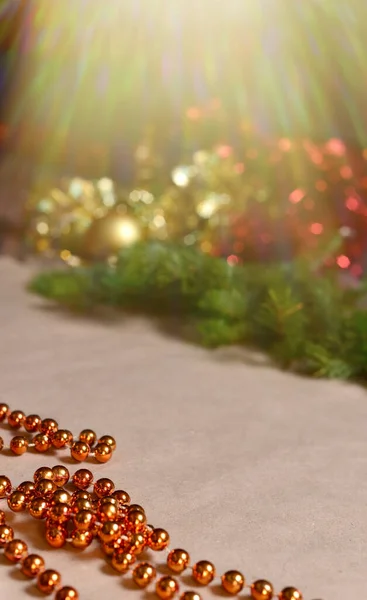 Háttér kézműves papír narancssárga gyöngyök, arany és piros tinsel, zöld lucfenyő ágak. Díszítés, dekoráció az új évre és karácsonyra — Stock Fotó