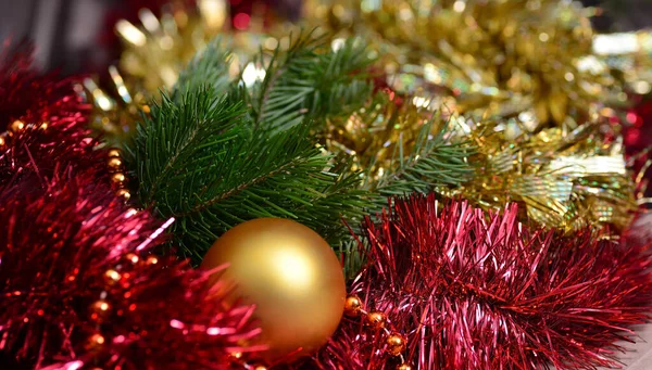 Ano Novo abstrato e Natal fundo horizontal longo. Tinsel vermelho e dourado, uma bola dourada está dentro, o fundo é borrado. — Fotografia de Stock