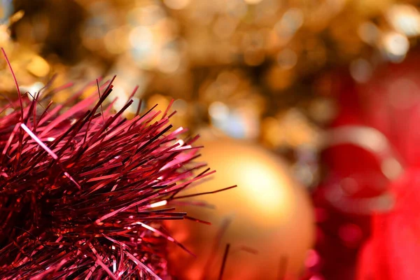 Abstrakt nyår och jul lång horisontell bakgrund. Röd och guld tinsel, en gyllene boll ligger inuti, bakgrunden är suddig. — Stockfoto