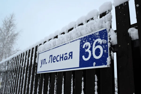 Un frammento di un recinto scuro con un cartello che indica il nome della strada: Lesnaya, trentasei. — Foto Stock