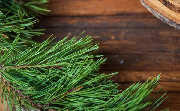 Branche vert pin avec de longues aiguilles sur une table en bois marron, vue de dessus. — Photo