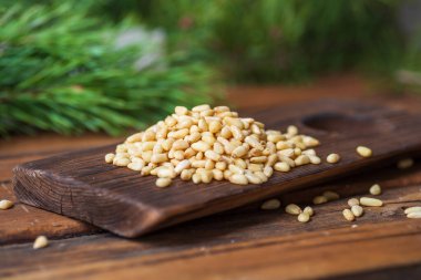 Soyulmuş çam fıstıkları koyu bir tahta kesme tahtasına yığılır.. 